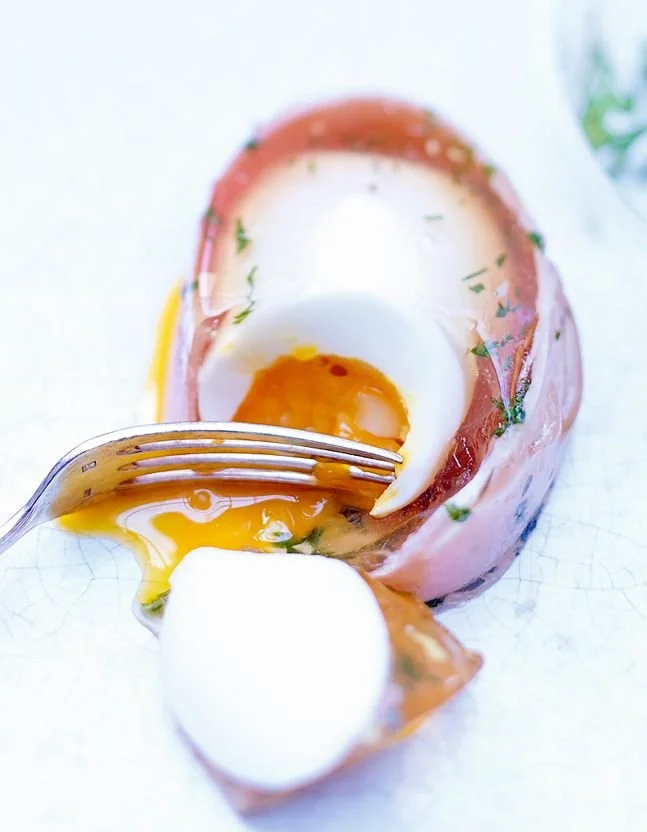 Oeufs en gelée présentés dans un plat élégant, garnis d'herbes fraîches.